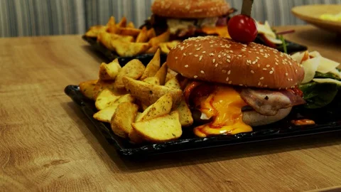 Two hamburger with salad and roasted potatoes on table moving camera slow motion Video stock 129140202