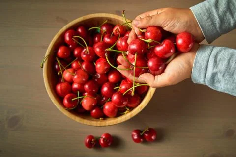 Two hand child boy spring red cherries on wooden background selective focus Stock Photos