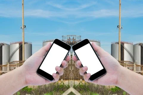 Two hand holding the black smartphone with Oil refinery industry with blue sk Stock Photos