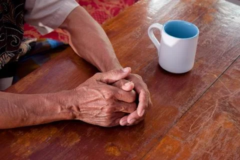 Two hand of senior elder on table, loneliness old man in living room with his Stock-Fotos