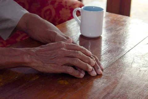 Two hand of senior elder on table, loneliness old man in living room with his Stock Photos