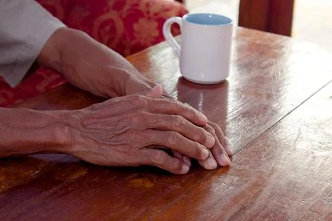 Two hand of senior elder on table, loneliness old man in living room with his Stock Photos