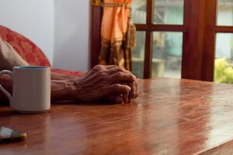 Two hand of senior elder on table, loneliness old man in living room with his Foto stock