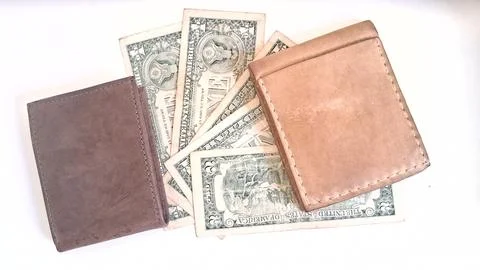 Two handcrafted leather wallets resting on several vintage paper banknotes Stock Photos
