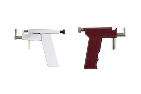 Two Handheld Ear piercing guns, one white and one red, sit side by side on a cle Stock Photos