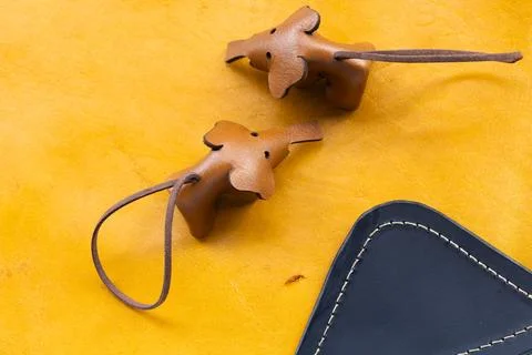 Two Handmade Leather Bear Keychains with Cord on Yellow Leather Surface Nex.. Фото
