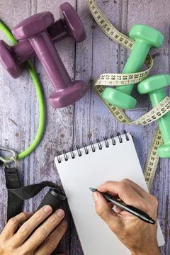 Two hands and a notepad, dumbbells, elastics and a measuring tape, concept .. Stock Photos