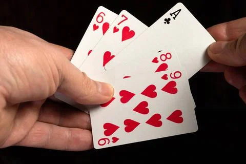 Two hands are holding playing cards with the image of hearts and one ace of.. Stock Photos