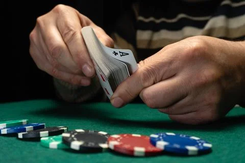 Two hands are mixing a deck of playing cards. Different colored poker chips.. Stock Photos