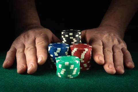 Two hands are placed on the green felt table holding stacks of poker chips... Foto stock