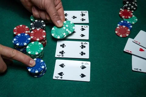 Two hands are seen spreading chips on a green table during a card game. Sev.. Stock Photos