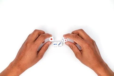 Two Hands Arranging White Dice with Red and Blue Dots on a White Background Stock Photos