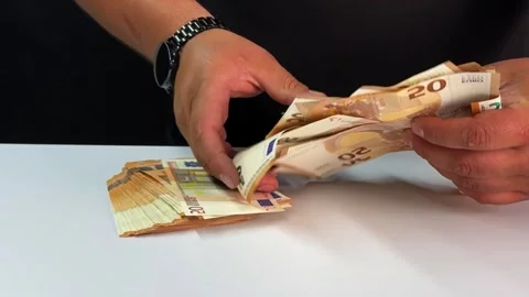 Two hands carefully sort through stacks of euro bills, arranging the notes Stock Footage 296775422
