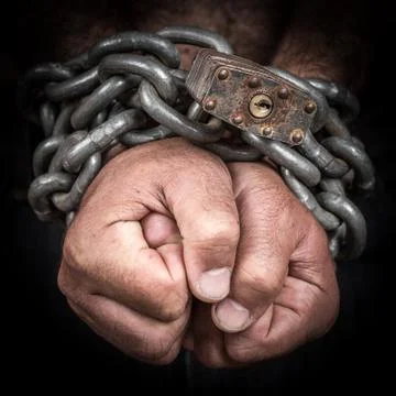 Two hands chained with an iron chain and a padlock Stock Photos