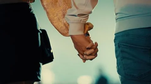 Two hands clasped tightly, one in white shirt, the other in dark pants Foto stock