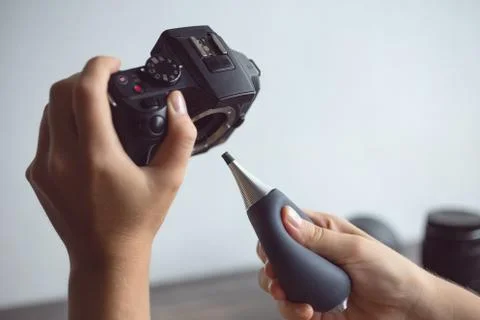 Two hands cleaning digital camera sensor from dust with air blower Stock Photos