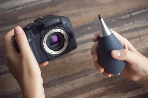 Two hands cleaning digital camera sensor from dust with air blower Stock Photos