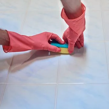 Two hands Cleaning a tile in the bathroom Stock Photos