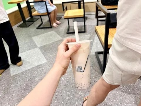 Two hands clinking bubble tea cups in a cafe. Fotos de archivo
