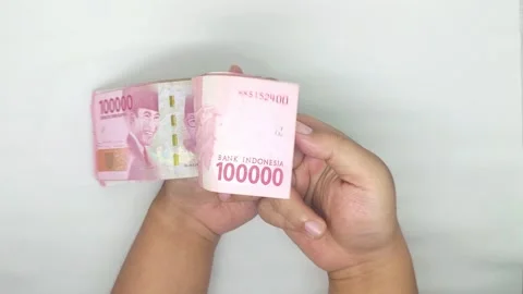 Two hands counting Indonesian banknotes in the 100,000 rupiah denomination Video stock 302318953