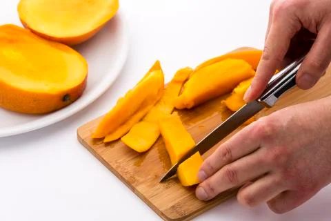 Two hands dicing a mango wedge with a first cut Stock Photos