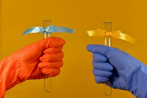 Two hands in different colors of rubber gloves. In each test tube with different Stock Photos