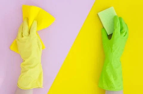 Two hands in different gloves holds sponge on yellow pink bright split color Stock Photos