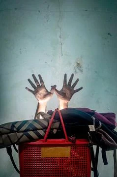 Two hands emerge above a red plastic basket filled with bags against a text.. Photos