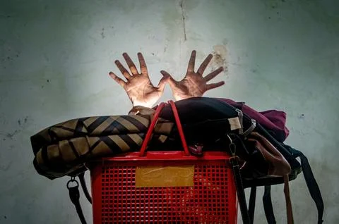 Two hands emerge from a red plastic basket filled with bags, creating a sur.. Stock Photos