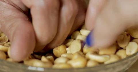 Two hands fighting each other over a bowl of salted, roasted, peanuts Video stock 92736190
