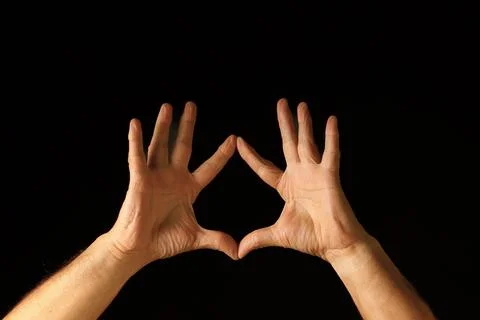 Two Hands Forming a Triangle Shape Against a Dark Background Stock Photos