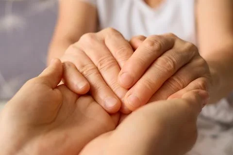 Two hands gently clasp together in a display of support and connection, hig.. Stock Photos