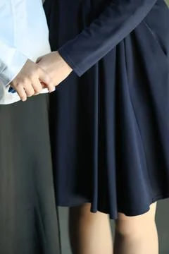 Two hands gently clasped together. One wears a navy dress, the other a whit.. Stock Photos