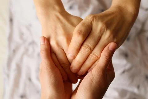 Two hands gently hold each other, conveying tenderness and warmth in a mome.. Stock Photos