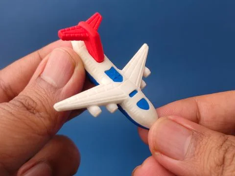 Two hands gently hold a miniature white toy airplane with blue accents and .. Stock Photos