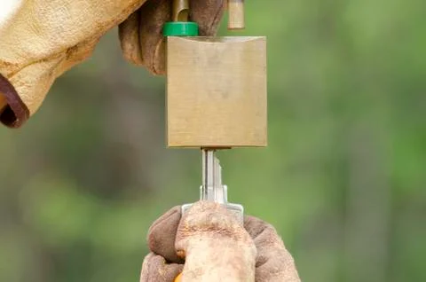 Two Hands in gloves with key and unlocked padlock. Stock-Fotos