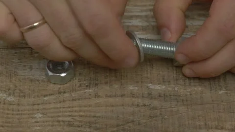 Two Hands Grasping a Coin and a Bolt on a Textured Wooden Surface for Artistic Видео 283458168