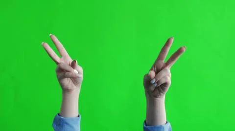 Two hands on a green background represent a peace sign. Isolated Stock Photos