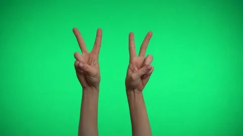 Two hands on a green background show the sign of peace. Video stock 163600304