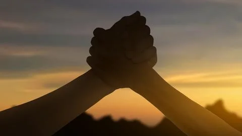 Two hands gripping each other tightly in a supportive gesture against a war.. Stock Photos