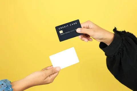 Two Hands Hold and Exchange Credit Cards on a Yellow Background Stock Photos