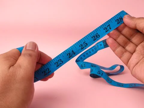 Two hands hold and unroll a coiled blue plastic measuring tape displaying n.. Stock Photos