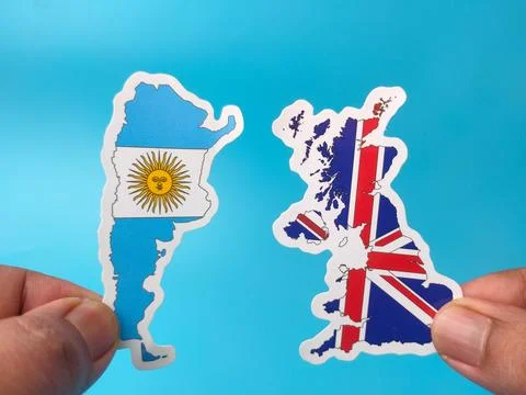 Two hands hold up country map stickers of Argentina and the United Kingdom .. Stock Photos