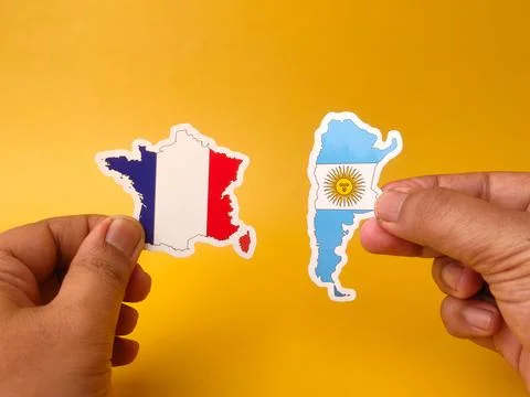 Two hands hold flag-patterned paper cutouts matching the geographic borders.. Stock Photos
