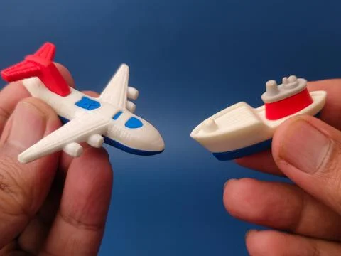 Two hands hold a miniature white and blue toy airplane and a small white an.. Stock Photos