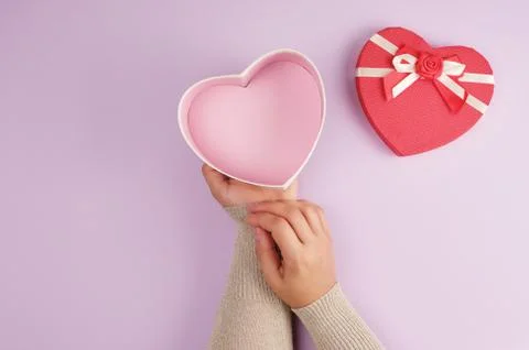 Two hands hold a paper open red box in the shape of a heart Stock Photos