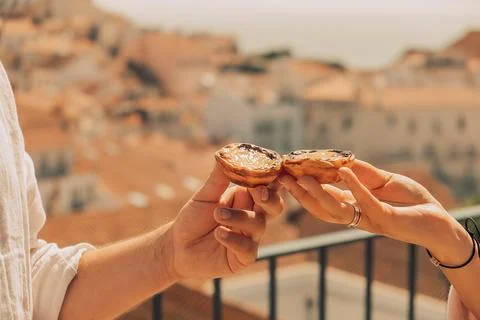 Two hands hold pastry while showing city in background during daylight hours  Fotos Stock