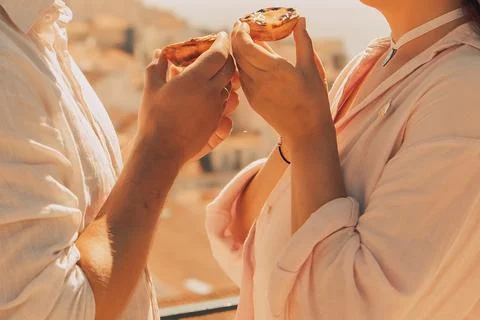 Two hands hold pastry while showing city in background during daylight hours  库存照片
