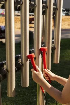 Two hands hold red mallets as they strike metal tubes producing musical sou.. Stock Photos
