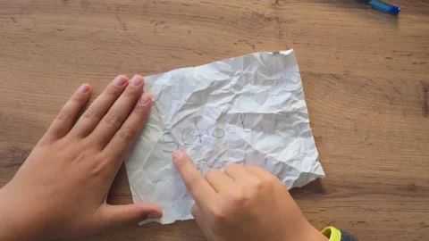 Two hands holding a crumpled white paper sheet with faint cursive writing Stock Footage 346450517